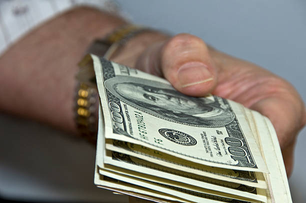 Offering US dollar bills in hand stock photo