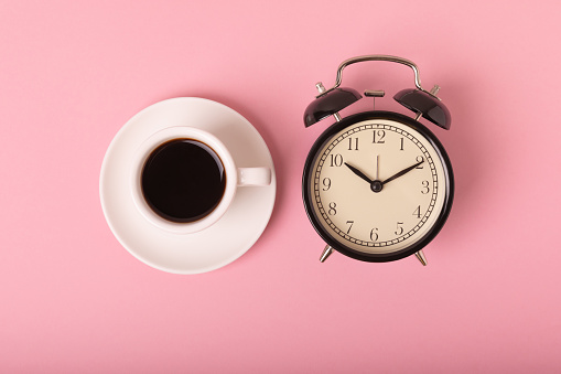 Alarm clock and coffee cup on color background.Good morning concept. Aroma, hot morning drink. Morning time concept. retro alarm clock and cup on background. WAKE UP. Good morning. flat lay.Banner.