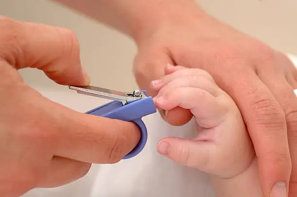 Close up of mum cutting babies long nails