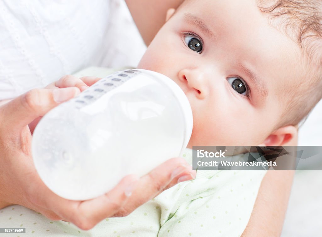 Close-up de um bebê bebendo leite nos braços de sua mãe - Foto de stock de Bebê royalty-free