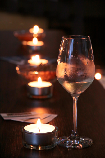 Wine glass in bar with line of tea lights