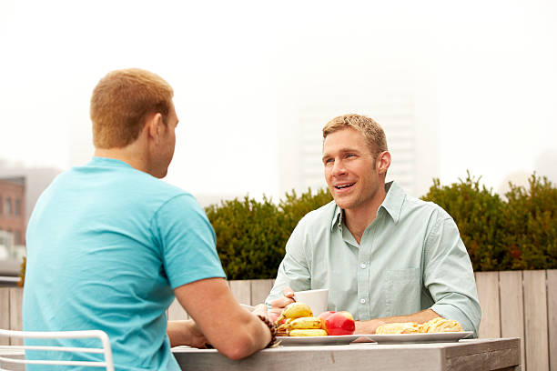 Two men having a healthy meal on patio stock photo