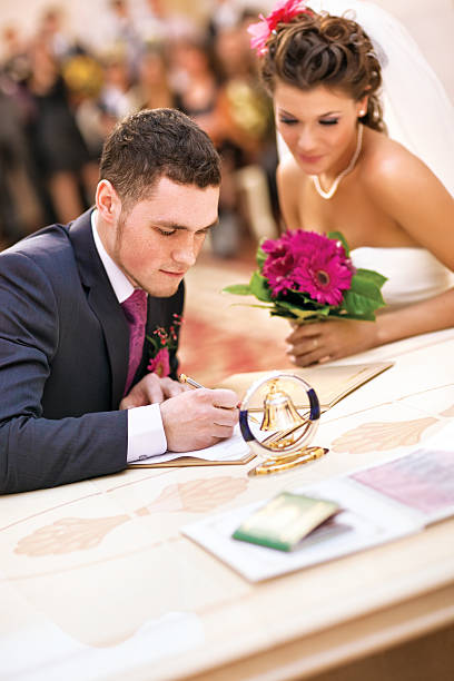 jeune couple de signer des documents de mariage - registry office photos et images de collection