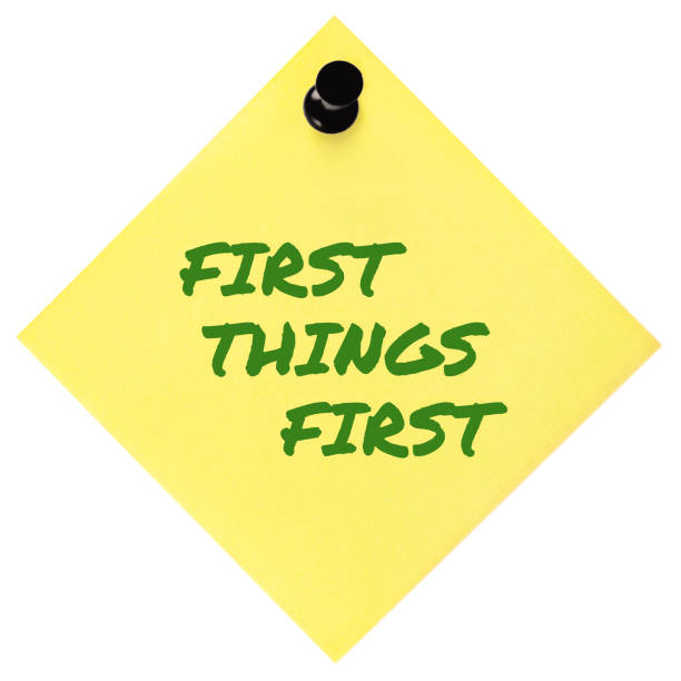istock First Things First reminder green marker handwritten motivational text, important crucial business priority action planning management concept metaphor, isolated yellow post-it to-do list sticky adhesive note sticker, black pushpin thumbtack macro closeup 1537517445