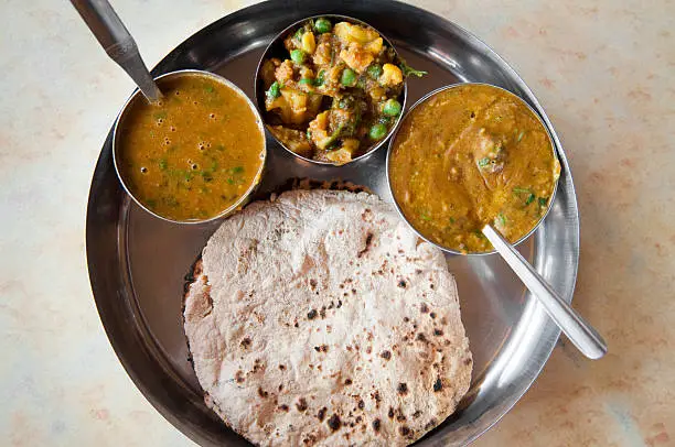 Traditional Indian cuisine vegetarian thali served in small bowls on a round tray.