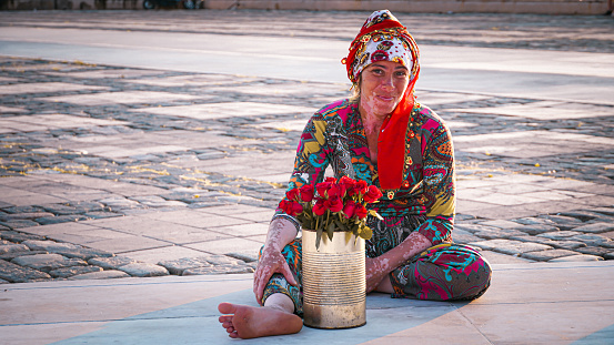 A gypsy woman with vitiligo skin disease is resting while selling flowers by the seaside in the center of Izmir, Turkey on 11.07.2023