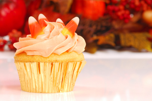 Delicious Halloween cupcake with butter cream frosting and fall foliage in the background