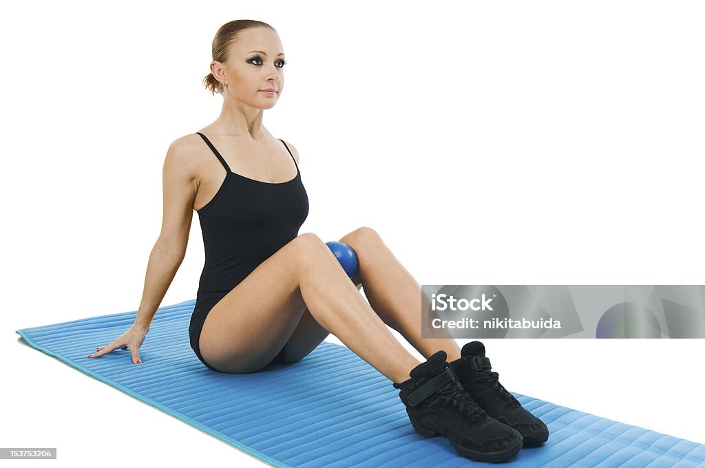 Beautiful red girl exercising with ball and yoga mat Beautiful fit red girl practicing pilates or callanetics with ball and blue yoga mat Activity Stock Photo