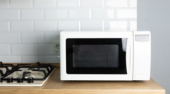 Modern white microwave on the kitchen countertop.Using microwave everyday in the kitchen. The concept of cooking.