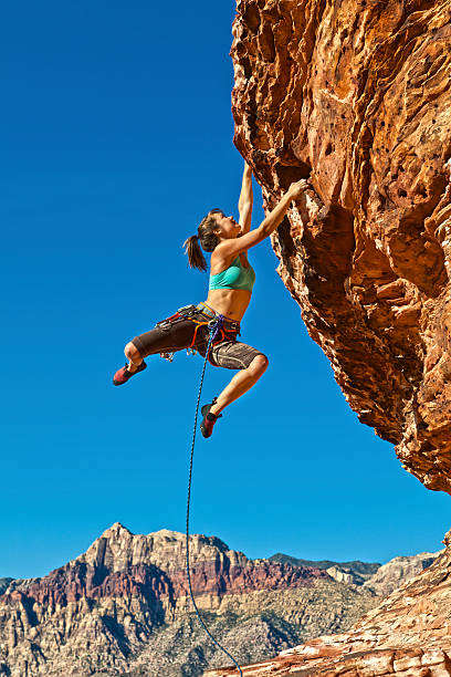 istock Female rock climber hanging on a cliff on a sunny day 153753908