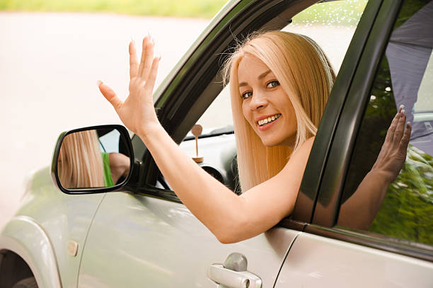 Driver-woman of car waves back stock photo