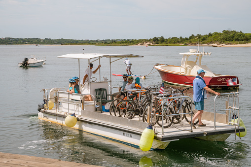 Menemsha, Chilmark, Martha's Vineyard, Massachusetts, US-July 26, 2022: People on bicycle ferry in quaint in iconic fishing village.
