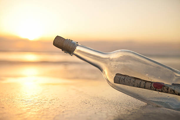 istock Message inside a glass bottle in a sand bank at the beach 153756532