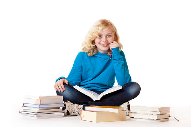 Schoolgirl sitting on floor and learning with study books stock photo