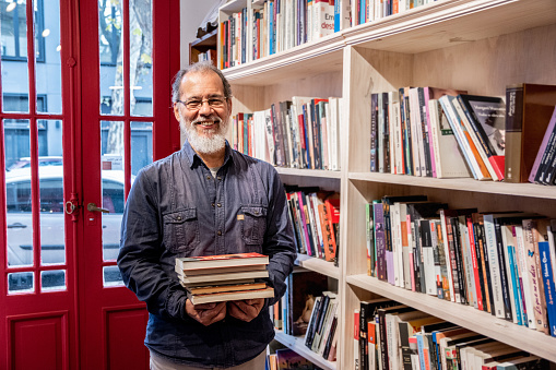 Senior man holding books in the library