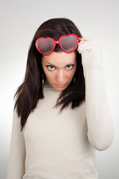 Girl removing heart shaped sunglasses stock photo