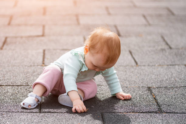 istock Toddler girl sitting on playground surface finds leaf 1537583627
