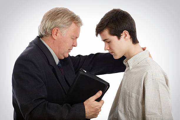 Evangelization of souls Pastor leading a young man in prayer to receive faith in Lord Jesus evangelic stock pictures, royalty-free photos & images