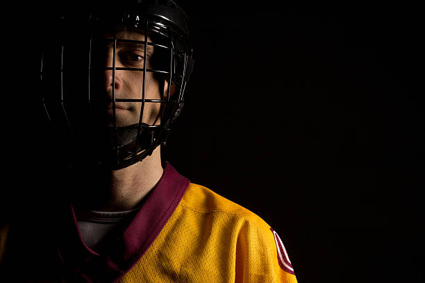 Concept of a Red Duotone Vector Stylized Photo Poster: Portrait of Confident Professional Hockey Player in Wire Cage Face Mask, Looking at Camera.