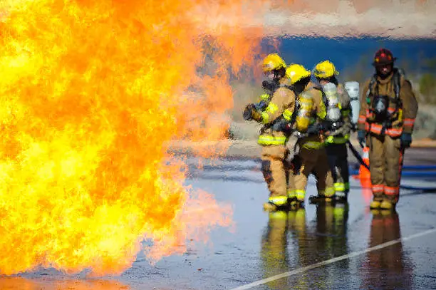 Heat waves partially obscure a team of firefighters preparing to attack a training fire.