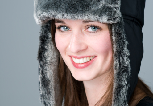 beautiful cheerful woman wearing a fur hat with blue eyes
