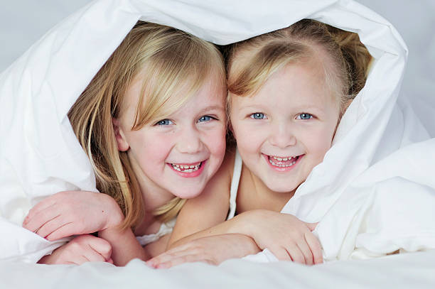 istock Two little girls under bed covers smiling. 153760765