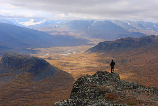 Hiker looking at a beautiful valley in autumn colors, Sweden.