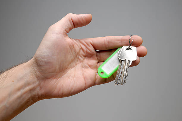 Left hand holding green key chain stock photo