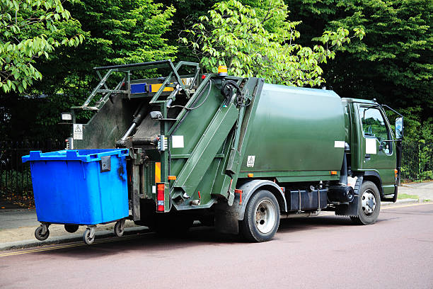 Garbage Truck Green garbage truck with an elevated blue wheelie bin at the rear garbage dump photos stock pictures, royalty-free photos & images