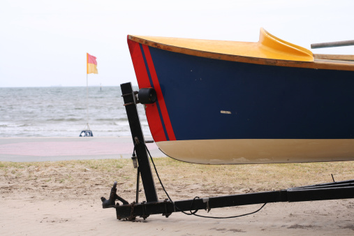 A beach life saving rescue boat with safety flag in background.