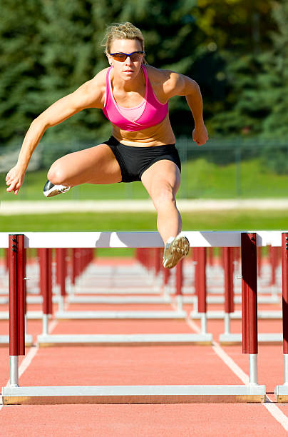 athlète sautant sur une piste de course de haies - track and field athlete women vitality speed photos et images de collection