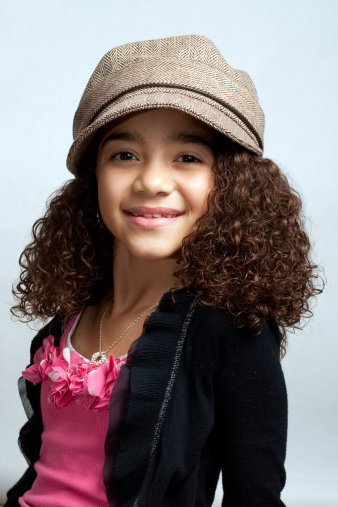 Young black girl wearing a big brown hat and smiling.