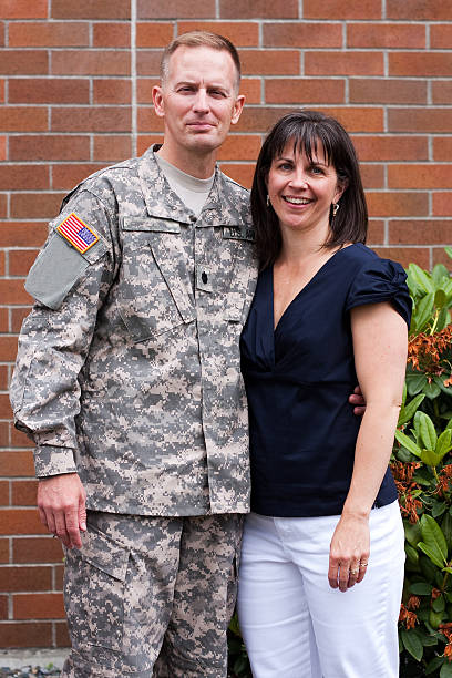 Soldier in fatigues with smiling wife beside brick building  stock photo