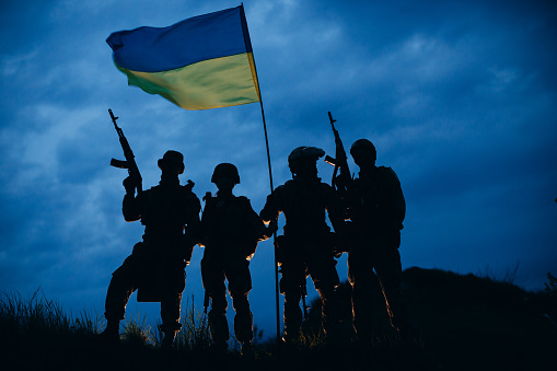 Un grupo de guerreros ucranianos armados con una bandera nacional por la noche photo