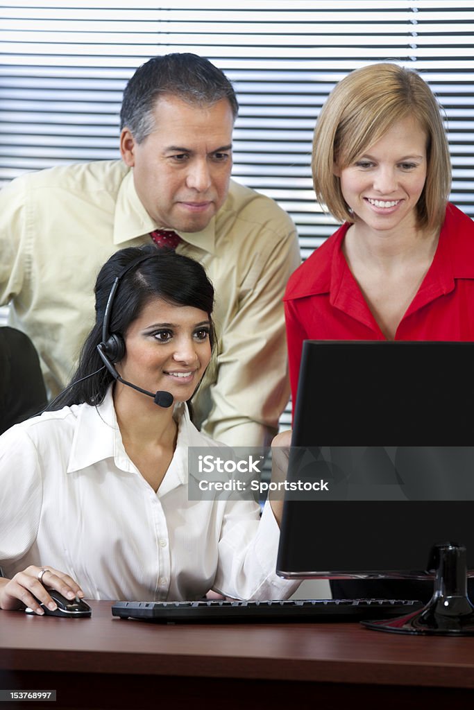 Business Team Looking At Computer Screen Two females and a male looking at computer screen in the office. Adults Only Stock Photo