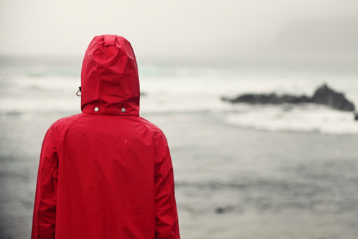 Fall xwoman in rain looking at ocean on grey day. Click for more: