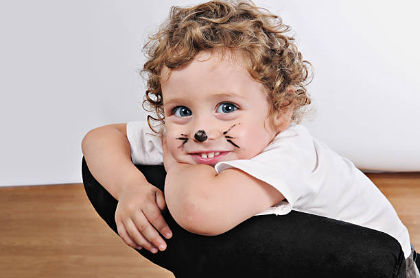 smiling blonde kid painted as kitty stock photo