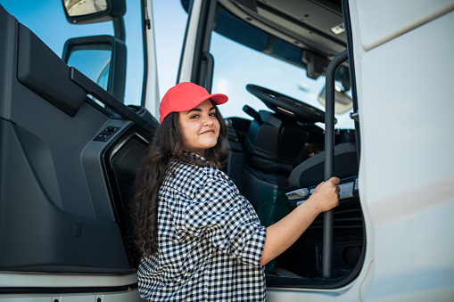 Smiling female truck driver getting in the truck.