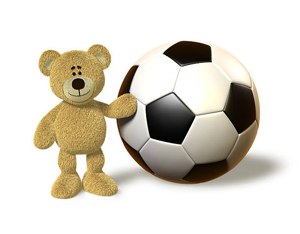 Teddy Bear stands next to a giant soccer ball, touches it with his left hand and smiles.