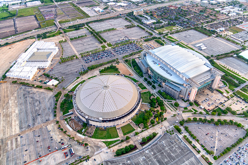 Houston, United States - April 13, 2023:  Aerial view of both the NRG Stadium, home to the NFL's Houston Texans, and the historic Astrodome, the first indoor sports arena, now listed as a historic site shot from an altitude of about 600 feet overhead during a helicopter photo flight.