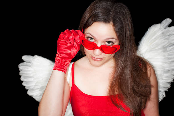 Sassy young woman with a red satin top and gloves and a knowing look peering over heart shaped glasses