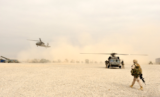 A Marine walks toward two landing blackhawk helicopters. It's just another day at the office for him.