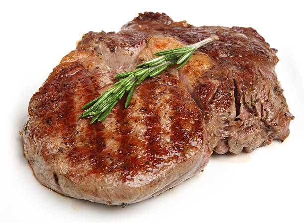 Close up of lone rib eye steak on white Juicy rib-eye beef steak with rosemary. rib eye steak stock pictures, royalty-free photos & images