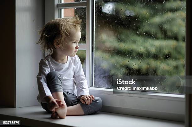 Adorable Toddler Girl Looking At Raindrops Stock Photo - Download Image Now - Rain, Window, 12-17 Months