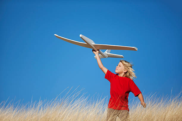 9-yr old male standing in grassy field about to fly a model airplane.