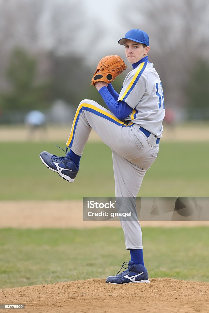 High school pitcher Caucasian high school teenage pitcher delivering baseball to home plate Baseball Pitcher Stock Photo