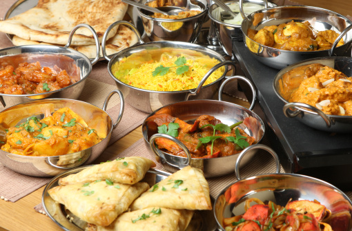 Selection of Indian food including curries, rice, samosas and naan bread.