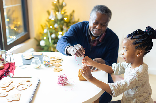 Christmas time. Grandfather and his granddaughter joyfully making gingerbread cookies