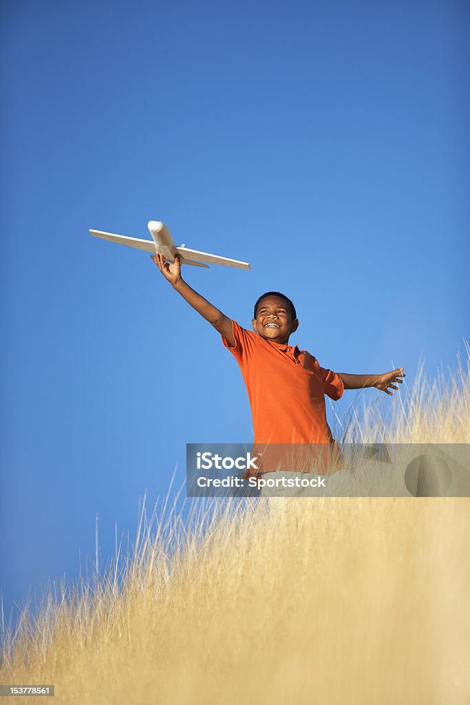 Ethnic Child Playing with Toy Glider Airplane in Field African-American boy standing in field playing with model airplane. Child Stock Photo