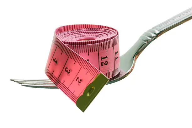 Pink tape-measure on fork isolated on white